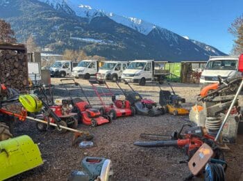 Firmenfahrzeuge, Rasenmäher und Gartenpflegegeräte von Pflanzenvielfalt Rupprechter vor der Tiroler Bergkulisse